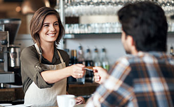 Barista in coffee shop handing a man his credit card