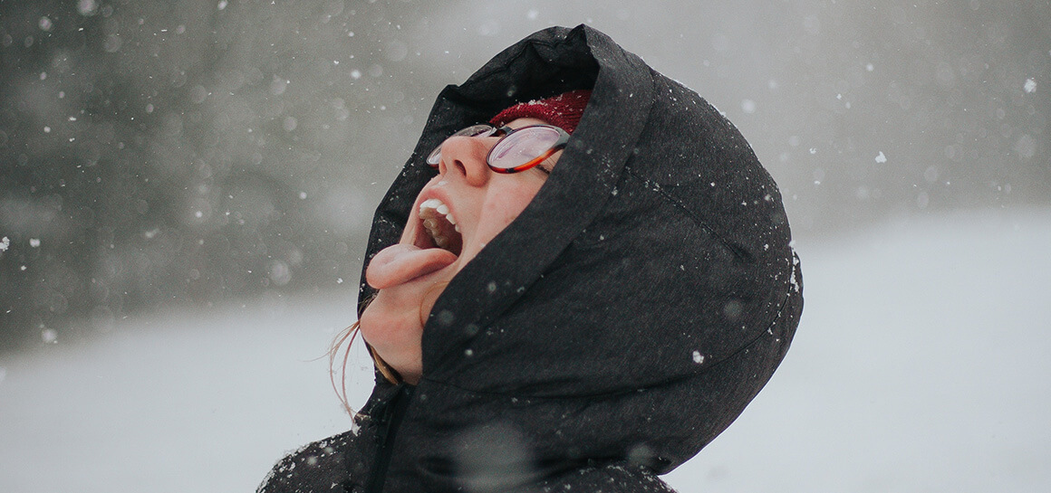 Women with head turned back and mouth open trying to catch snowflakes