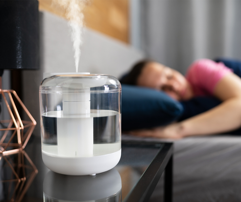 Humidifier on a nightstand next to a sleeping man.