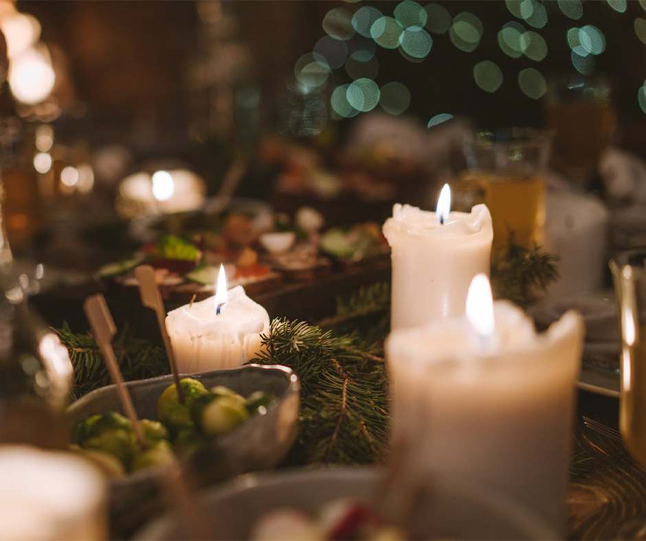 Candles burning on a table with holiday decorations and food. Image credit: Anastasia Shuraeva