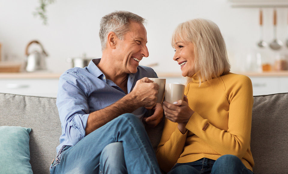 A couple sitting in Elmwood Manor living room drinking coffee