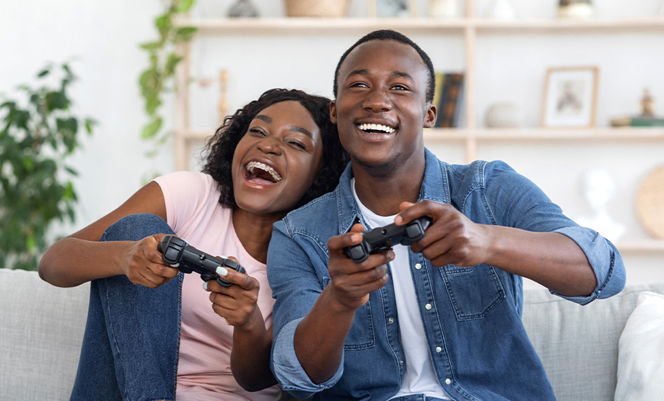 A woman and man sitting on a couch playing video games