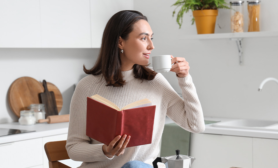 A woman drinking coffee in her Elmwood Manor kitchen